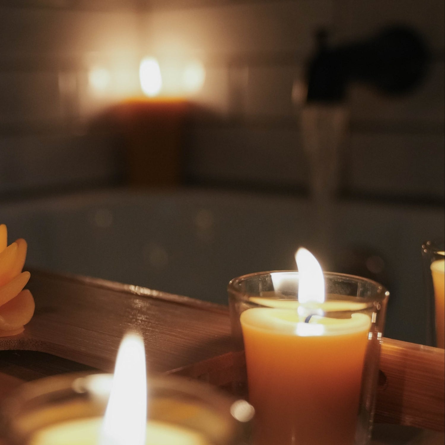Beeswax candles burning as a bath fills with water.