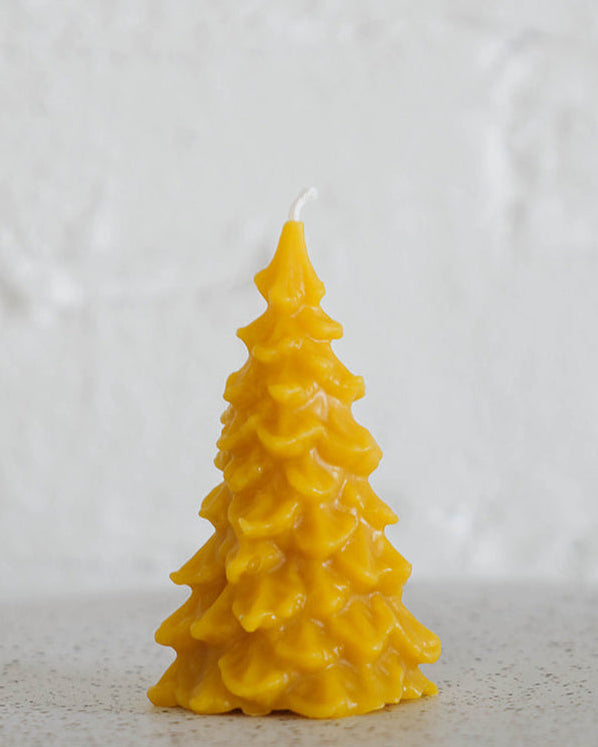 Beeswax candle shaped like a Christmas tree on a neutral background