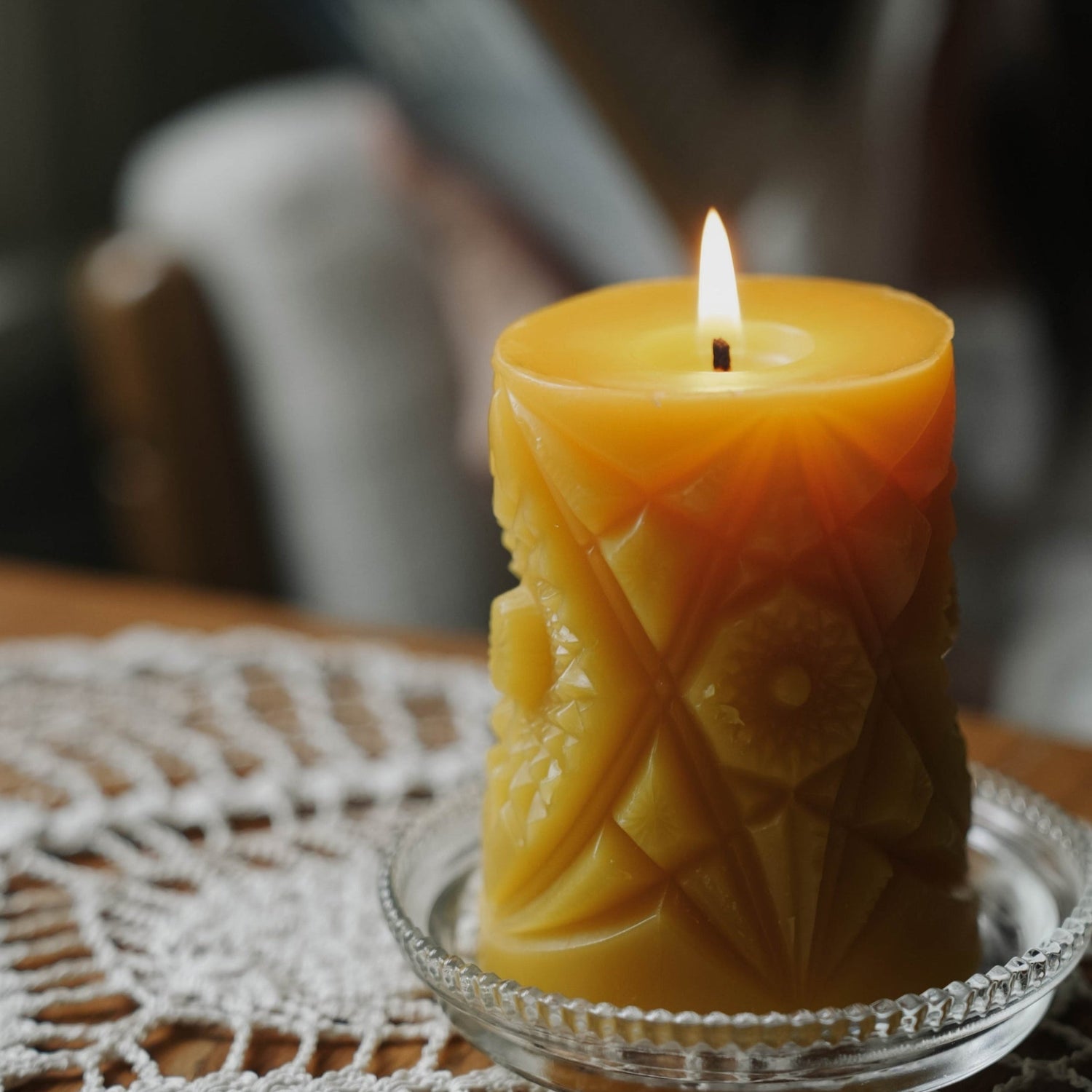 The golden flame of a geometric pattern beeswax pillar candle.