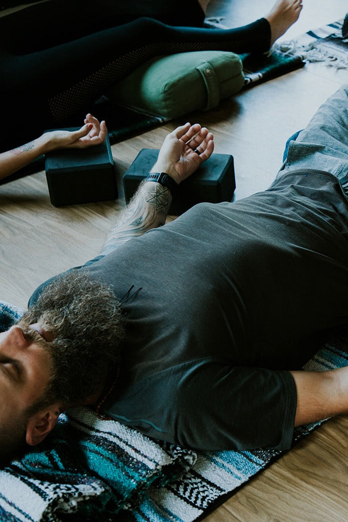Man laying in a prop-supported savasana during a yoga class.