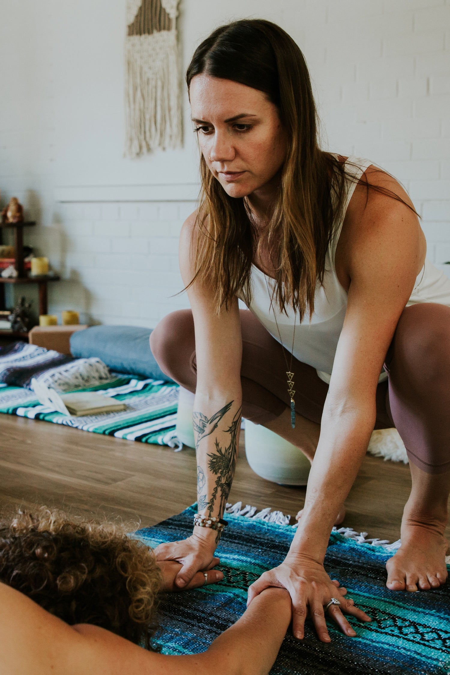 Yoga teacher grounding the hands of a student in a Yin yoga class.