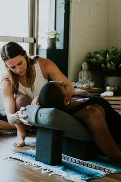 Yoga teacher adjusting the props of a student in a Yin posture.